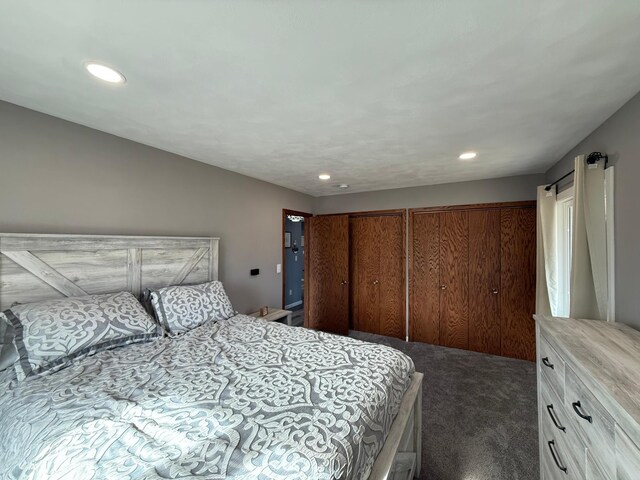 bedroom featuring recessed lighting, multiple closets, and dark colored carpet