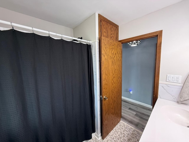 full bathroom featuring curtained shower, wood finished floors, baseboards, and a sink