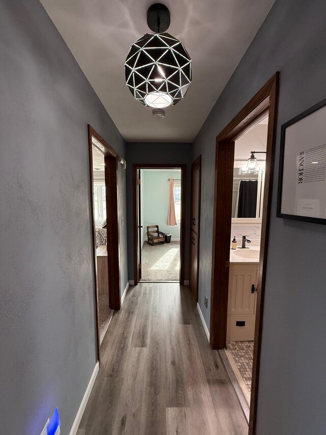 hallway with a sink, baseboards, and wood finished floors