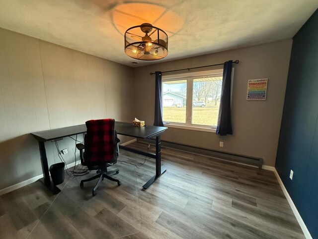 home office featuring a baseboard heating unit, baseboards, and wood finished floors