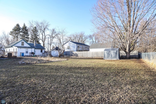 view of yard featuring a greenhouse, an outdoor structure, and a fenced backyard