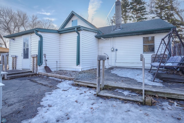 rear view of property with a wooden deck and a shingled roof