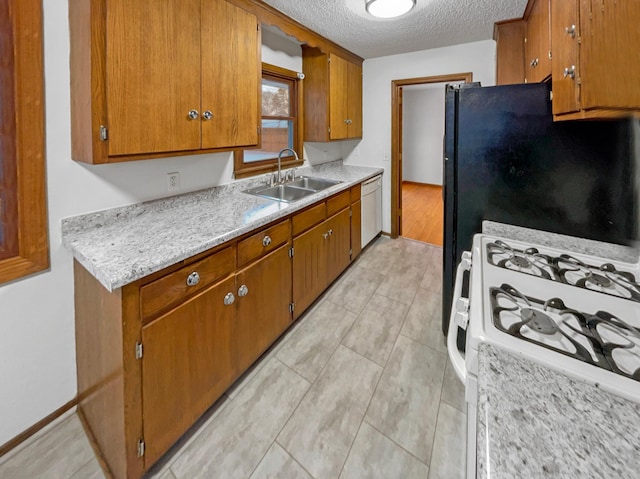 kitchen featuring brown cabinets, a sink, a textured ceiling, white appliances, and light countertops