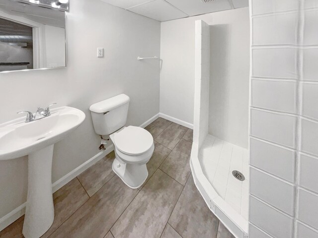 full bathroom with baseboards, a stall shower, a sink, tile patterned flooring, and toilet