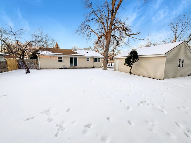 snow covered rear of property featuring fence