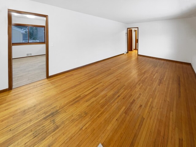 empty room with baseboards and light wood finished floors