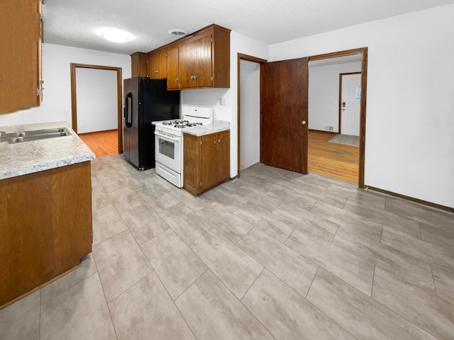 kitchen featuring visible vents, white gas stove, a sink, a textured ceiling, and light countertops