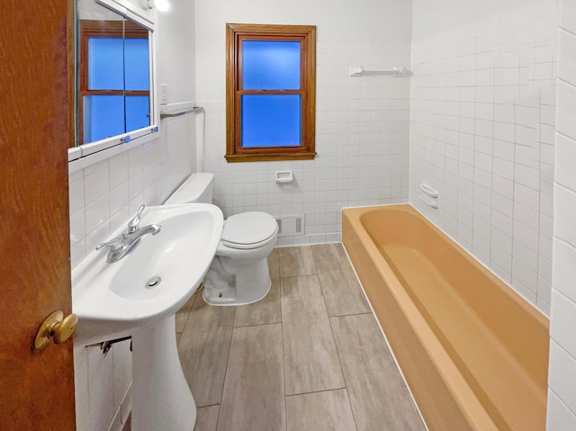 full bathroom with a sink, visible vents, toilet, and tile walls