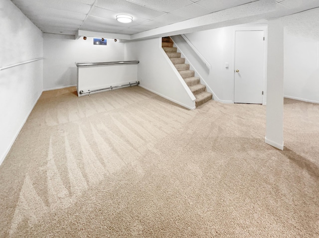 finished basement with stairway, carpet, baseboards, and a paneled ceiling