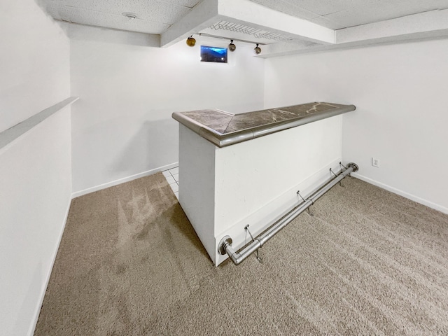 interior space featuring baseboards, a bar, and carpet flooring