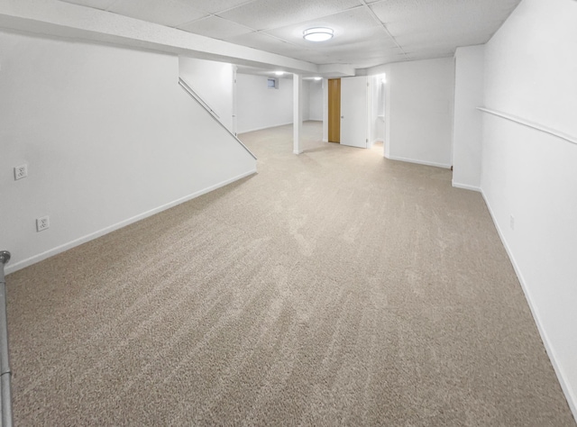 finished basement with a drop ceiling, baseboards, and carpet floors