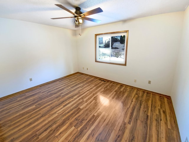 empty room featuring baseboards, ceiling fan, and wood finished floors