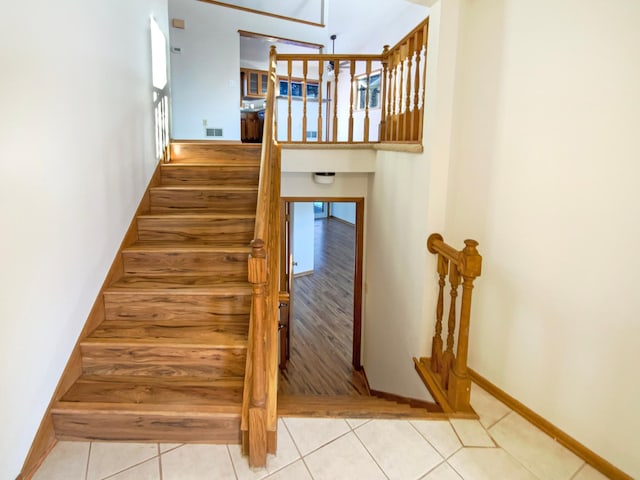 staircase featuring tile patterned flooring, visible vents, and baseboards