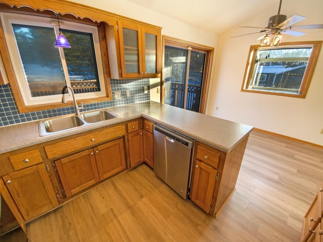 kitchen featuring brown cabinetry, a peninsula, a sink, dishwasher, and light wood-type flooring