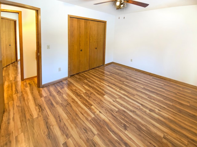 unfurnished bedroom featuring ceiling fan, wood finished floors, a closet, and baseboards