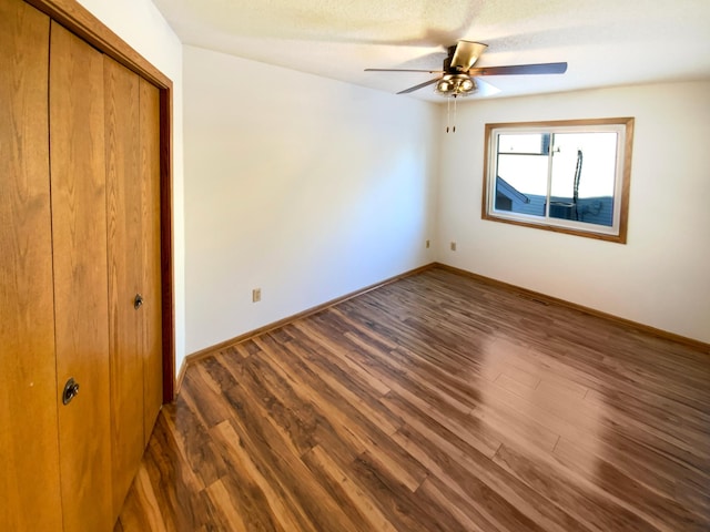 unfurnished bedroom with ceiling fan, wood finished floors, a closet, and baseboards