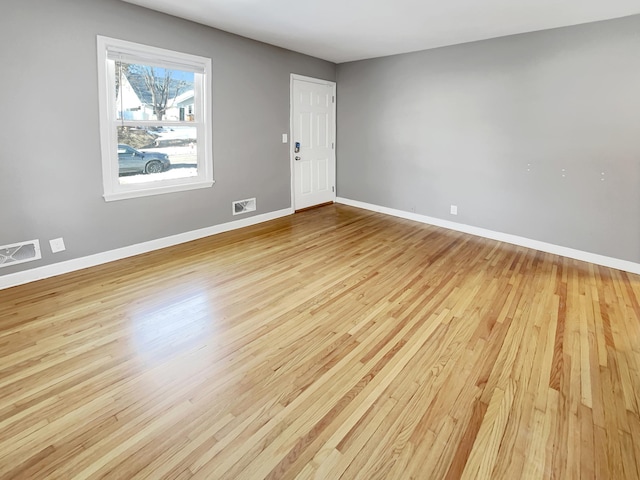 empty room featuring visible vents, light wood-type flooring, and baseboards