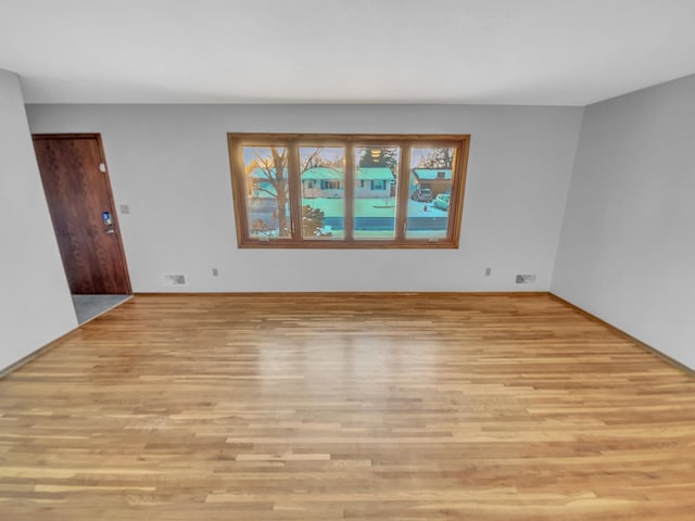 unfurnished room with wood finished floors and visible vents