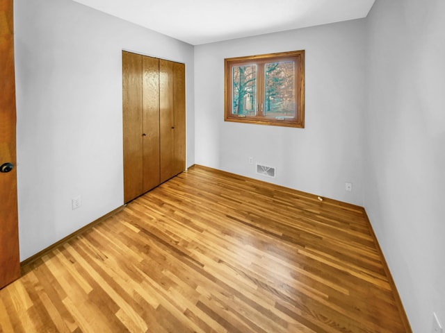 unfurnished bedroom with a closet, visible vents, and wood finished floors