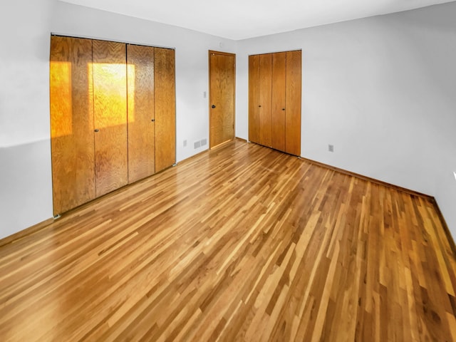 unfurnished bedroom featuring visible vents and wood finished floors