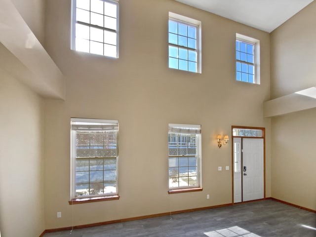 entryway with a towering ceiling, baseboards, and wood finished floors