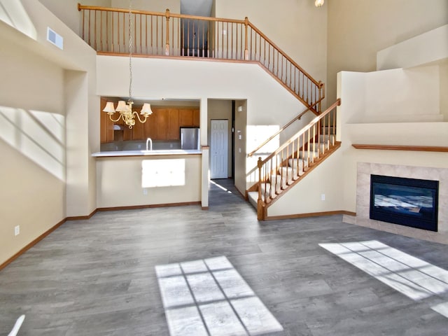 unfurnished living room with wood finished floors, a notable chandelier, baseboards, and visible vents