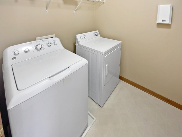 clothes washing area featuring baseboards, light floors, laundry area, and washing machine and clothes dryer