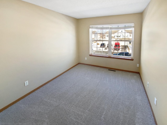 empty room featuring visible vents, baseboards, and light carpet