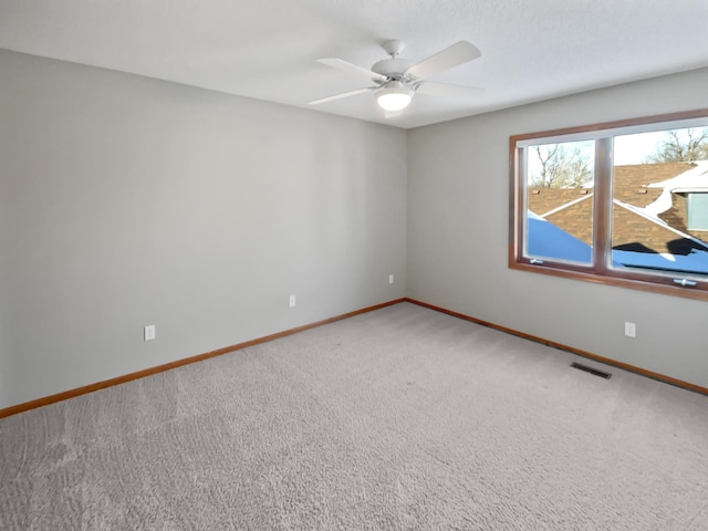 carpeted spare room featuring visible vents, baseboards, and a ceiling fan