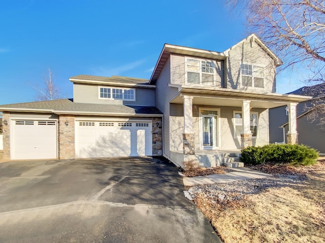 view of front of home featuring stone siding, covered porch, driveway, and a garage