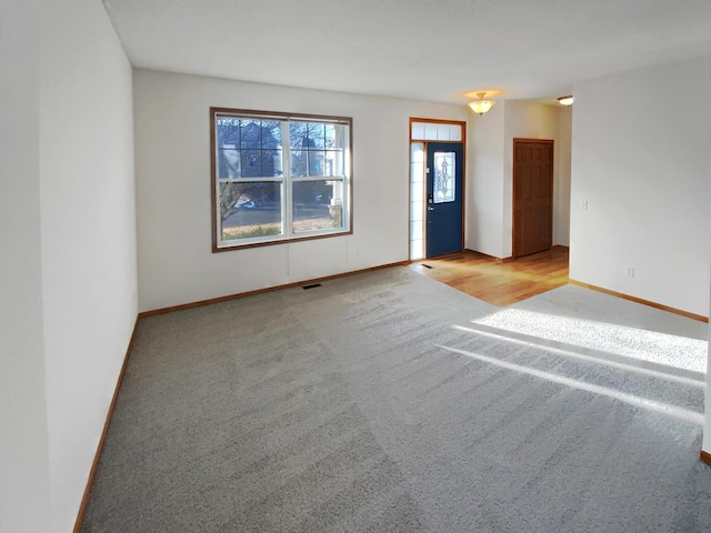 unfurnished room featuring baseboards, visible vents, and light carpet