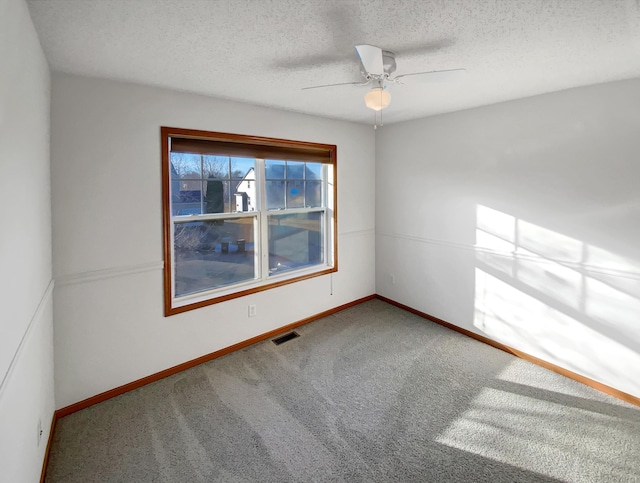 carpeted empty room featuring visible vents, baseboards, a textured ceiling, and a ceiling fan