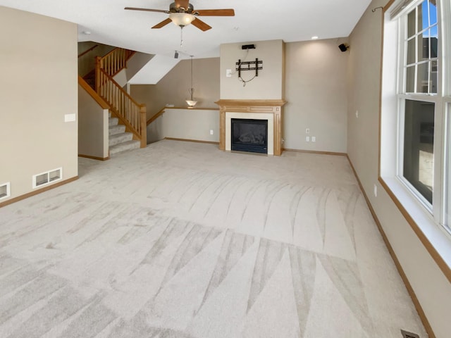 unfurnished living room with visible vents, baseboards, stairs, carpet flooring, and a glass covered fireplace