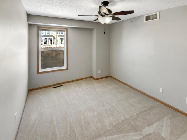 unfurnished room with visible vents, light colored carpet, a textured ceiling, and baseboards