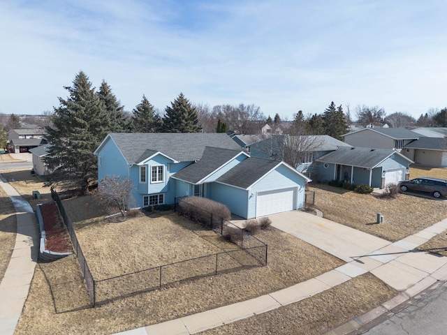 view of front of house featuring driveway, fence, a residential view, roof with shingles, and an attached garage