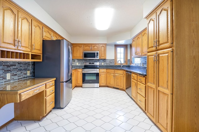 kitchen with dark countertops, decorative backsplash, stainless steel appliances, and a sink