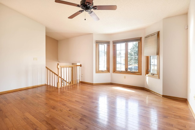 unfurnished room with baseboards, a textured ceiling, and hardwood / wood-style floors