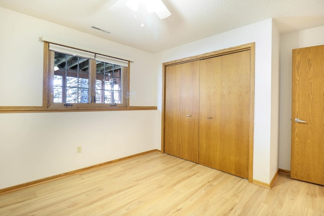 unfurnished bedroom with a closet, baseboards, visible vents, and wood finished floors