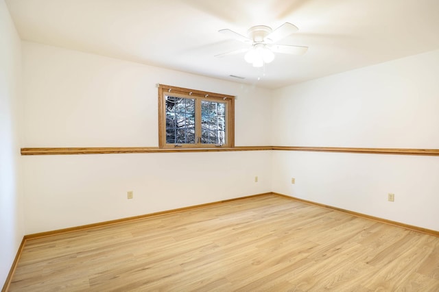 empty room featuring a ceiling fan, light wood-type flooring, and baseboards