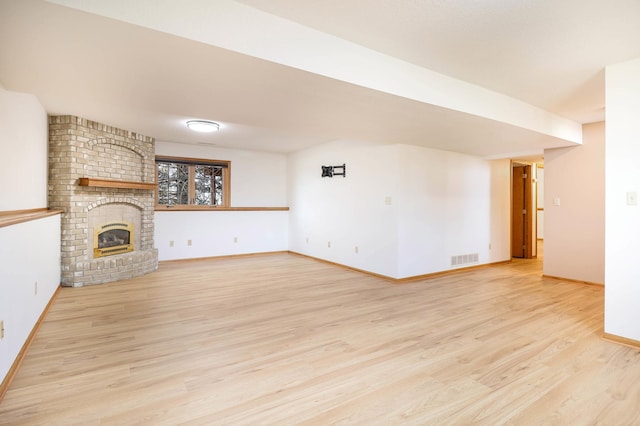 unfurnished living room with visible vents, baseboards, light wood-style floors, and a fireplace