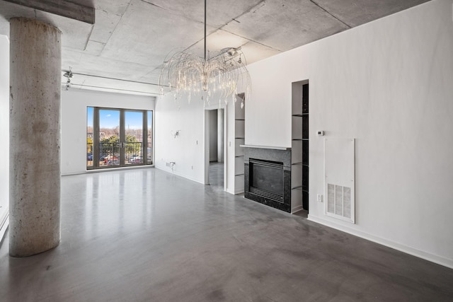 unfurnished living room with visible vents, concrete floors, baseboards, a fireplace, and a notable chandelier