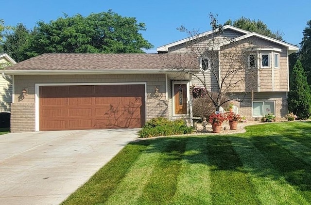 tri-level home with a front yard, roof with shingles, an attached garage, concrete driveway, and brick siding