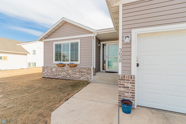 property entrance featuring a garage, brick siding, and a yard