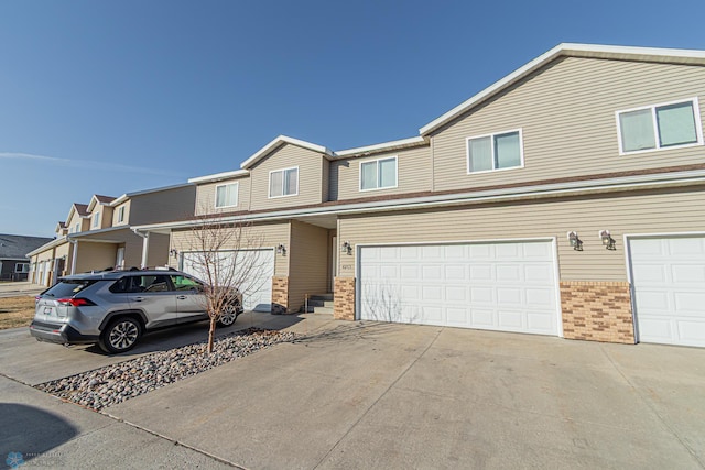 multi unit property featuring brick siding, a residential view, driveway, and an attached garage