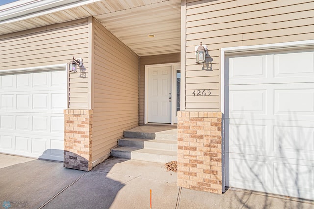 entrance to property featuring a garage and brick siding