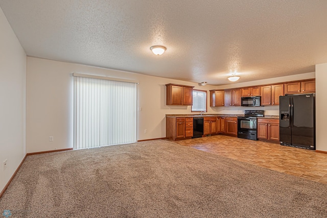 kitchen with brown cabinetry, baseboards, a sink, black appliances, and light colored carpet