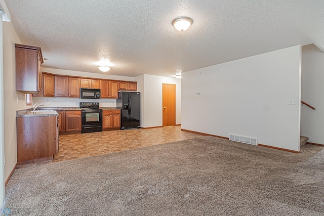 kitchen featuring brown cabinetry, visible vents, black appliances, light colored carpet, and open floor plan