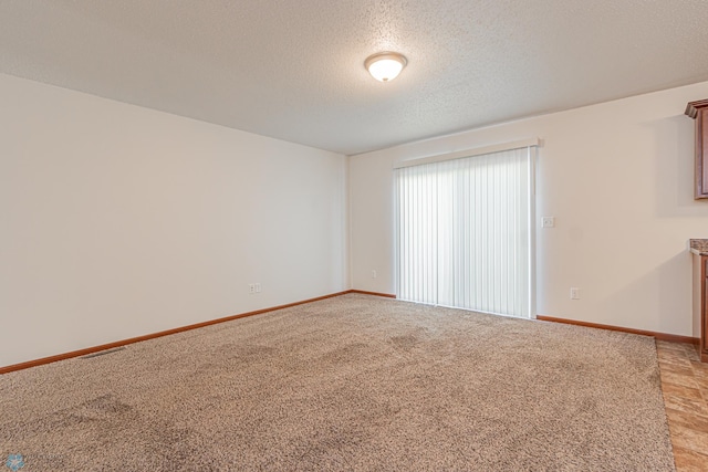 spare room featuring visible vents, baseboards, a textured ceiling, and light colored carpet