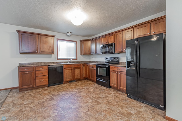 kitchen featuring baseboards, a sink, black appliances, dark countertops, and brown cabinets