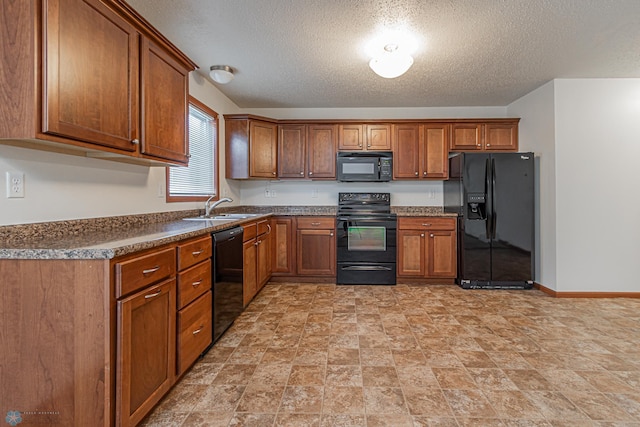 kitchen with black appliances, brown cabinetry, baseboards, and a sink